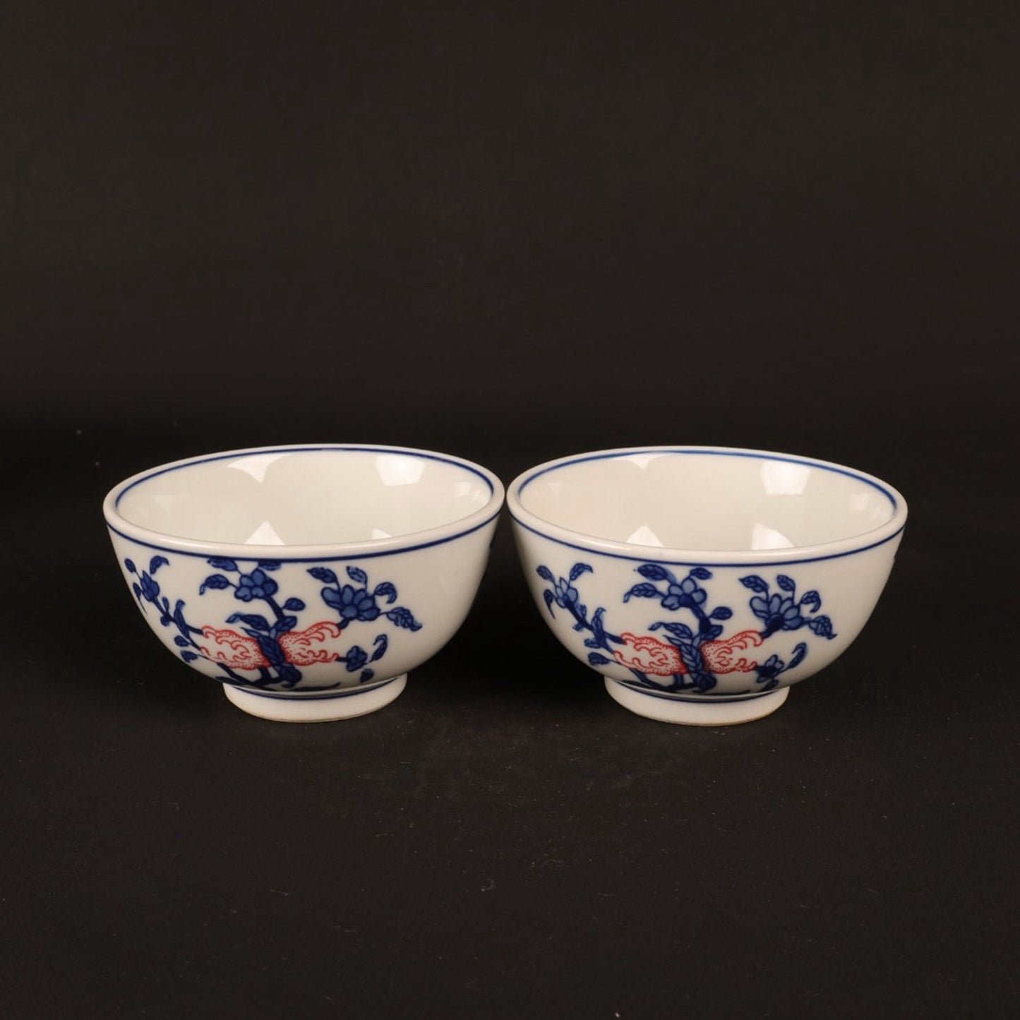 A pair of hand pressure cups with blue and white enamel, red blessings and longevity pictures