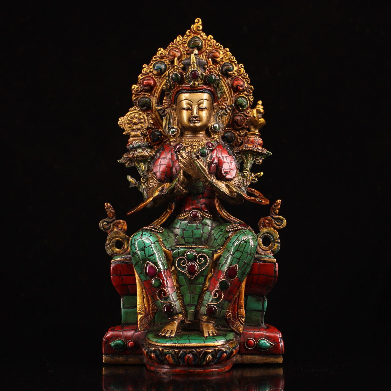 A pure copper handmade statue with inlaid gemstones, colorful paintings, and golden depictions, featuring a Buddha statue