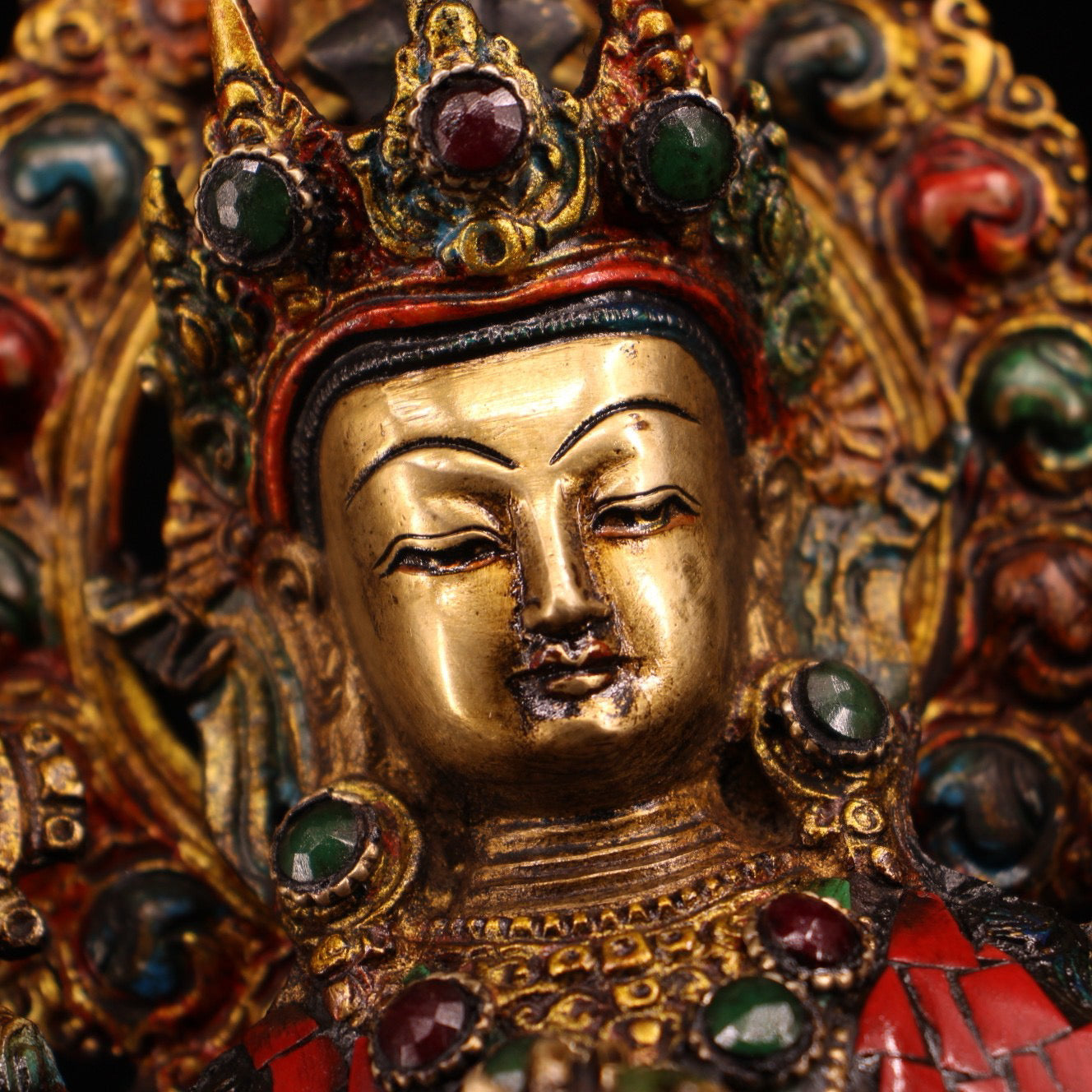 A pure copper handmade statue with inlaid gemstones, colorful paintings, and golden depictions, featuring a Buddha statue