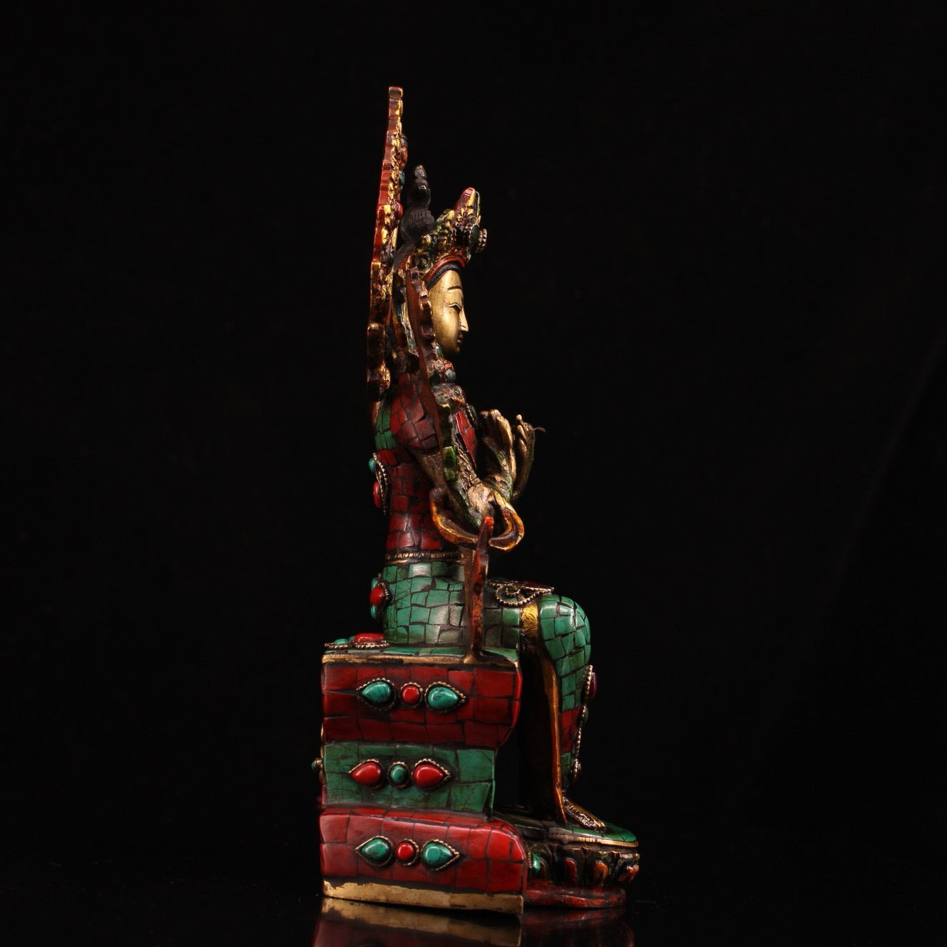 A pure copper handmade statue with inlaid gemstones, colorful paintings, and golden depictions, featuring a Buddha statue