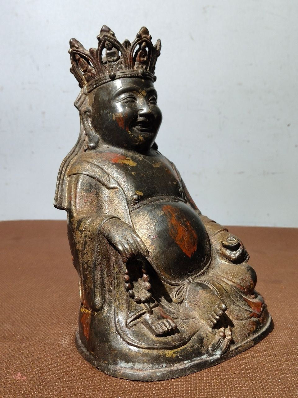 A statue of Maitreya Buddha with a large belly, made of copper, mud, gold, blooming, and sprinkled with cinnabar