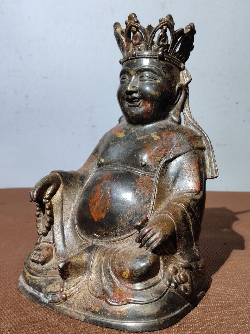 A statue of Maitreya Buddha with a large belly, made of copper, mud, gold, blooming, and sprinkled with cinnabar