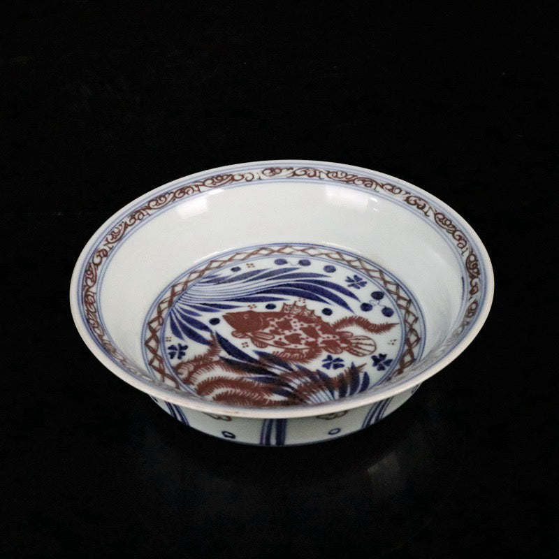 Blue and white glazed dish with red fish and algae patterns