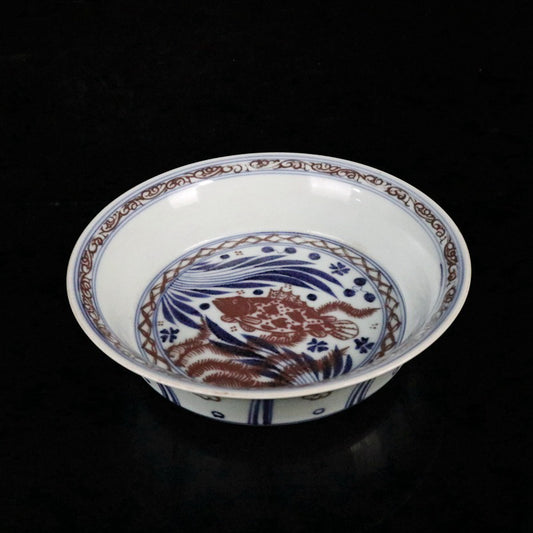 Blue and white glazed dish with red fish and algae patterns