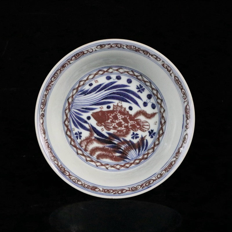 Blue and white glazed dish with red fish and algae patterns