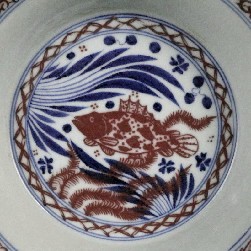 Blue and white glazed dish with red fish and algae patterns