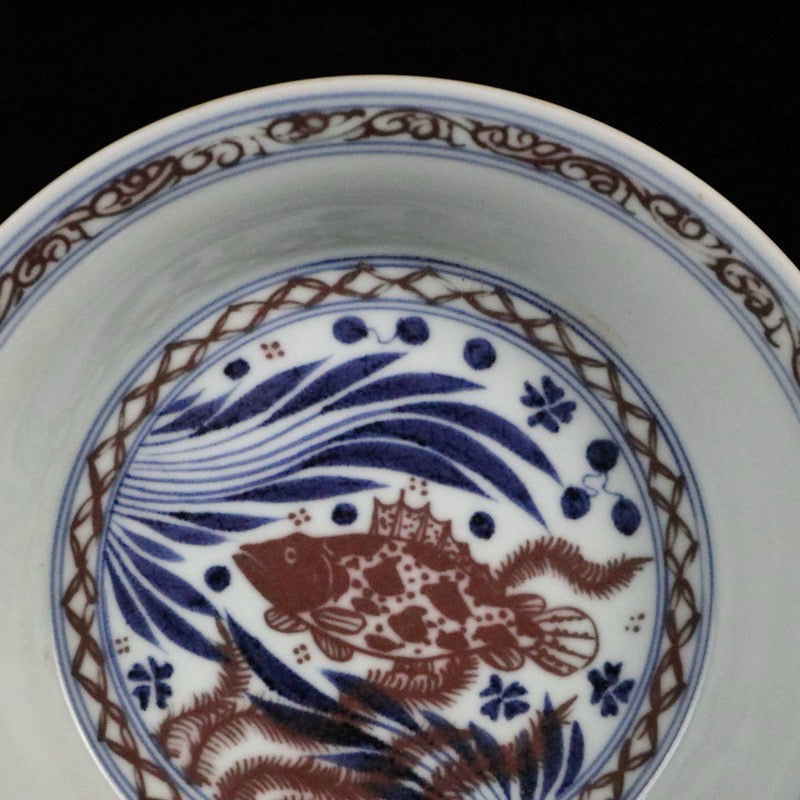 Blue and white glazed dish with red fish and algae patterns