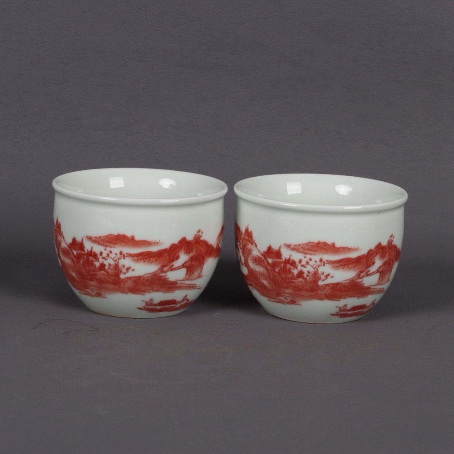 A pair of glazed red landscape patterned mouth cups