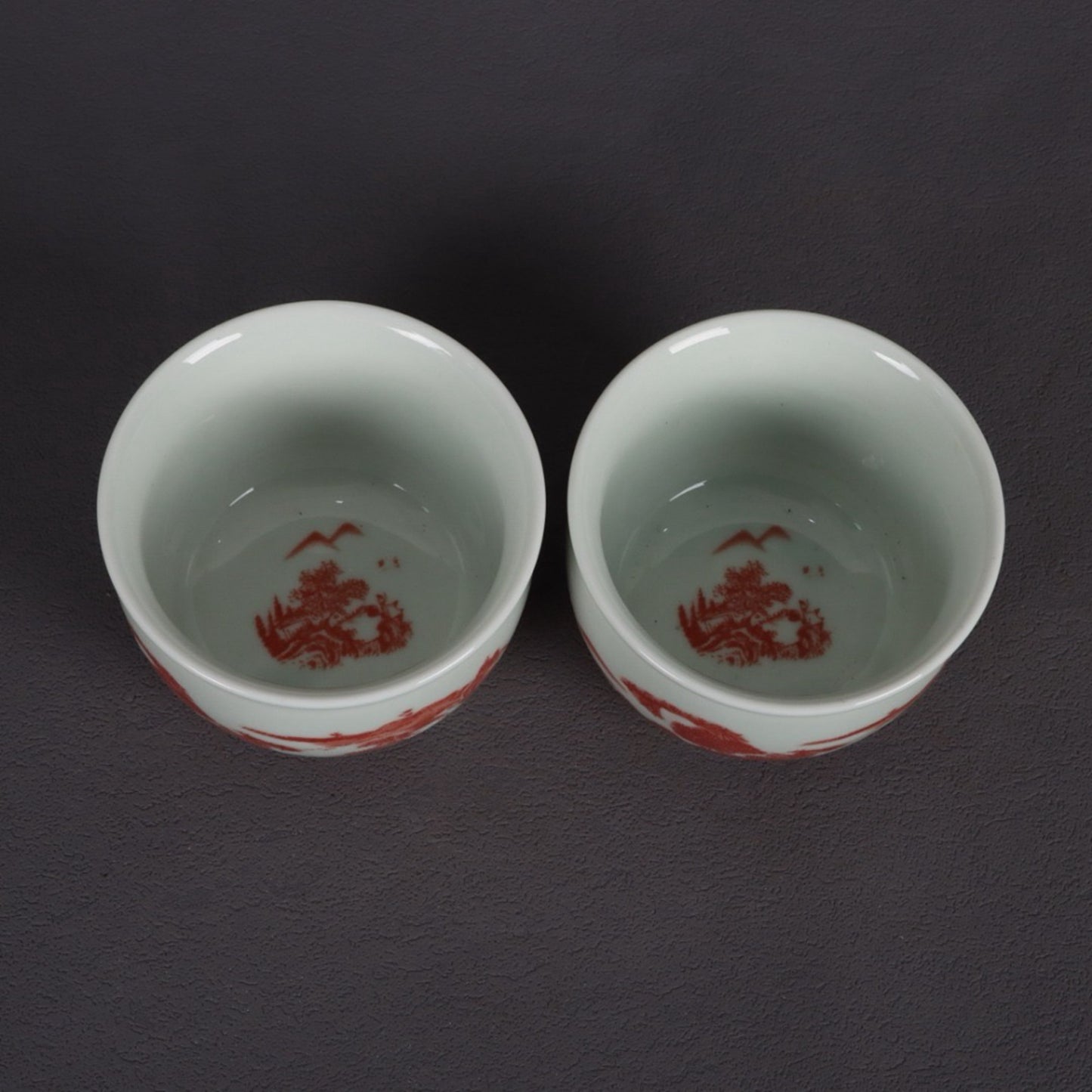 A pair of glazed red landscape patterned mouth cups