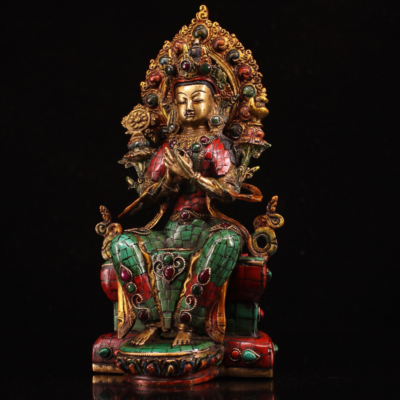 A pure copper handmade statue with inlaid gemstones, colorful paintings, and golden depictions, featuring a Buddha statue