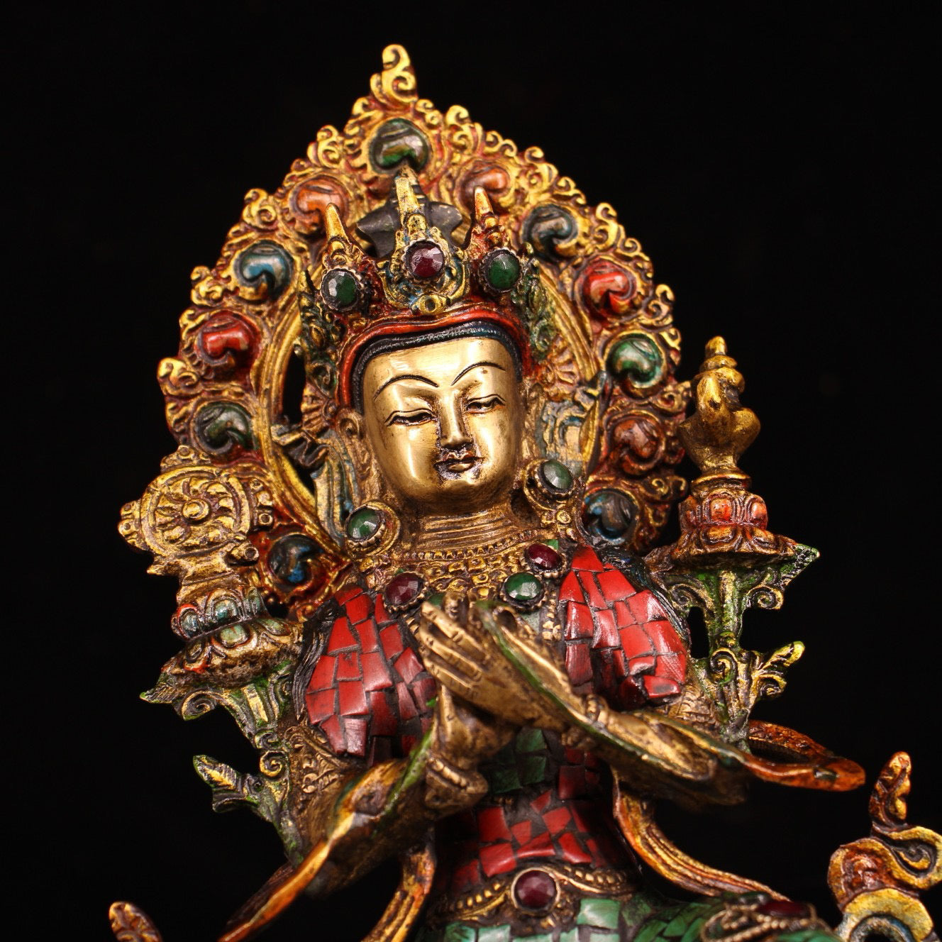 A pure copper handmade statue with inlaid gemstones, colorful paintings, and golden depictions, featuring a Buddha statue